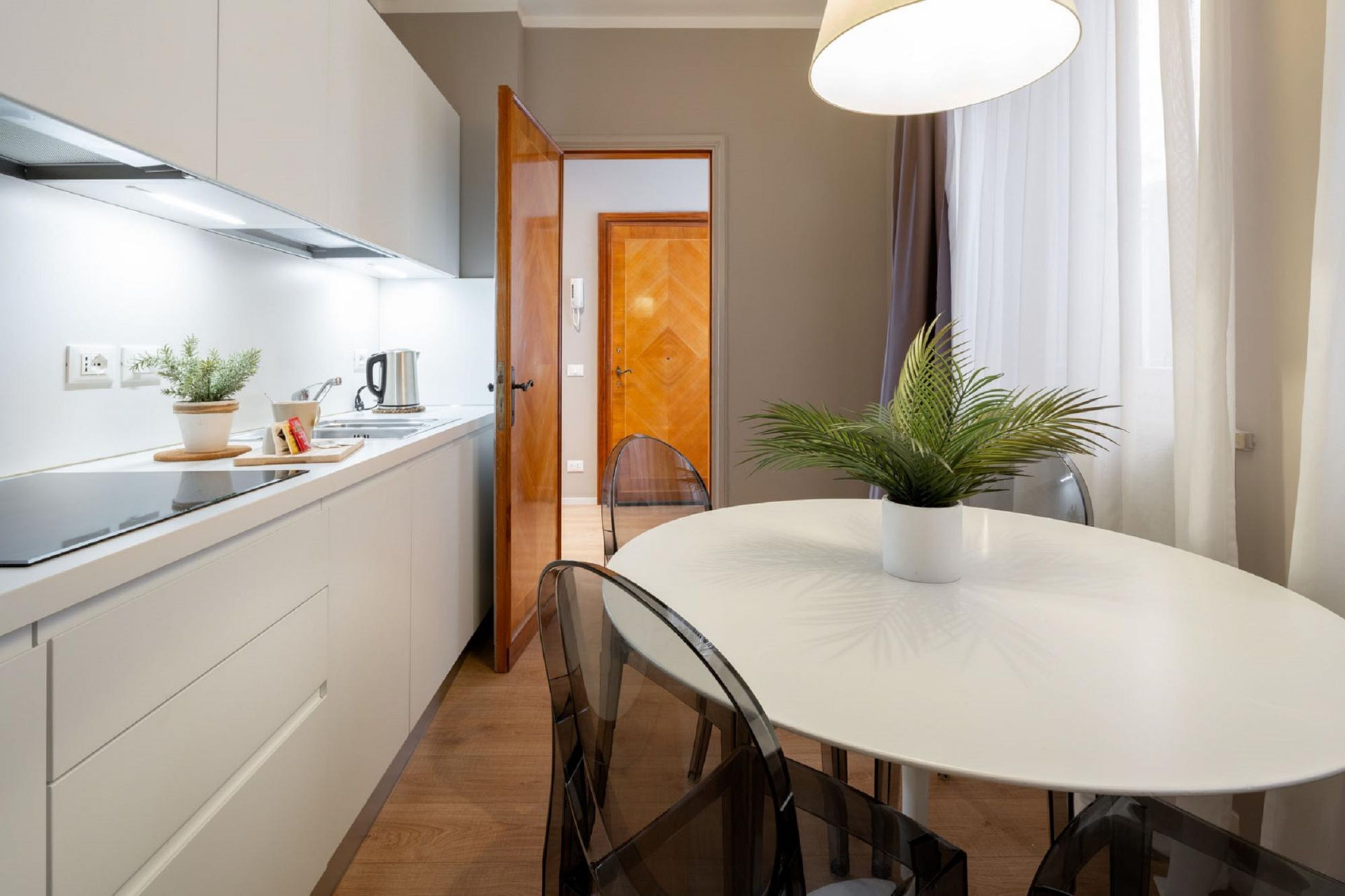 A modern kitchen with white cabinets, a black countertop, and a white dining table with chairs.