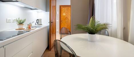 A modern kitchen with white cabinets, a black countertop, and a white dining table with chairs.
