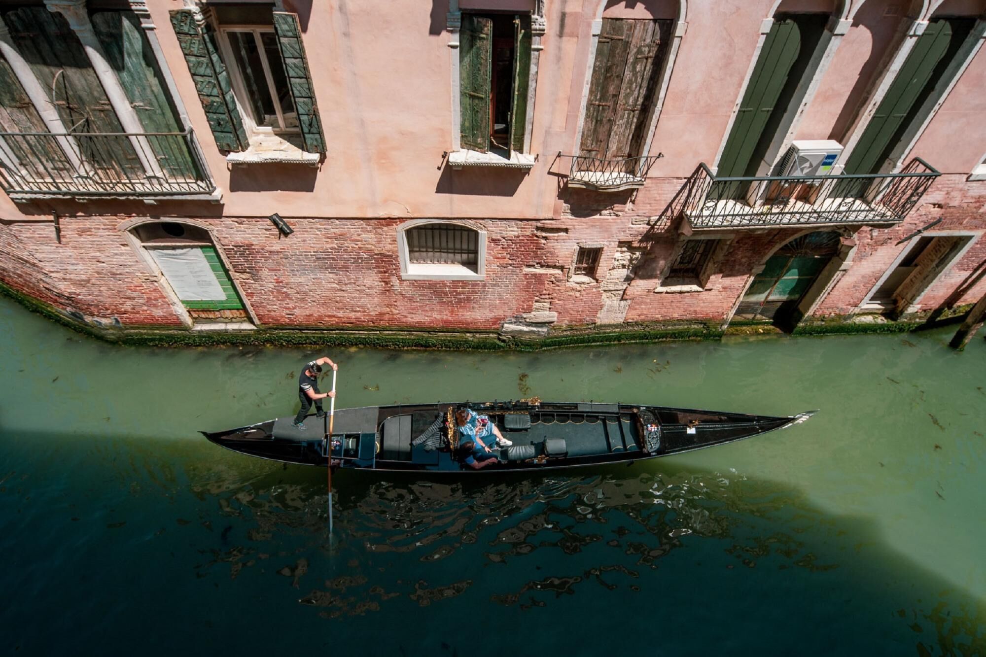 A narrow canal with a boat docked at a building with multiple windows and balconies.