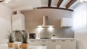 Una cucina moderna con mobili bianchi, un'isola centrale e una cappa aspirante in acciaio inossidabile.