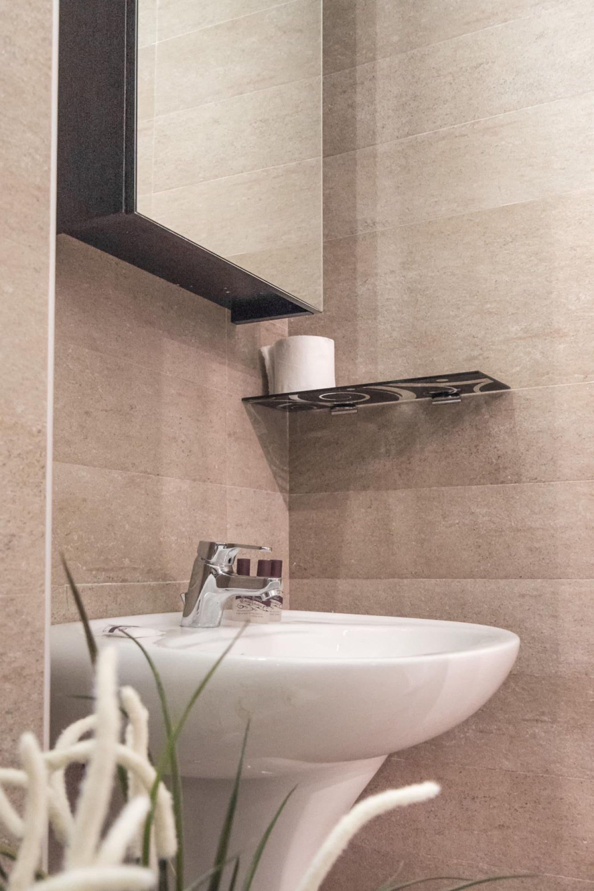 Une salle de bain avec un lavabo blanc, un miroir au-dessus et un porte-serviettes.