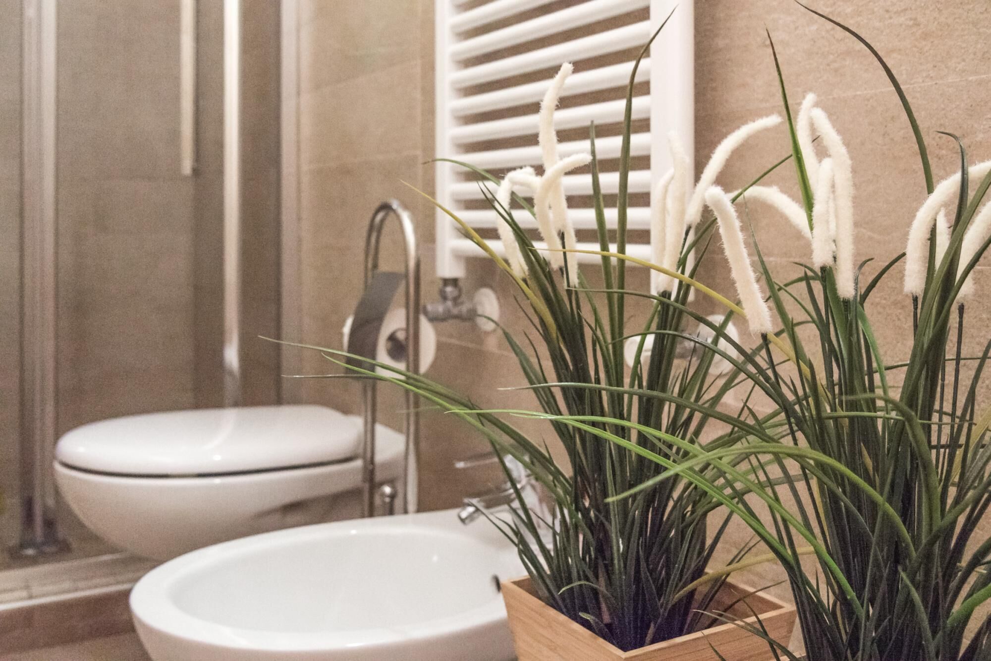 A bathroom with a toilet, sink, and a wooden planter with green plants.