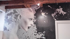 Una stanza con un grande quadro astratto sulla parete, un soffitto in legno e una porta bianca.
