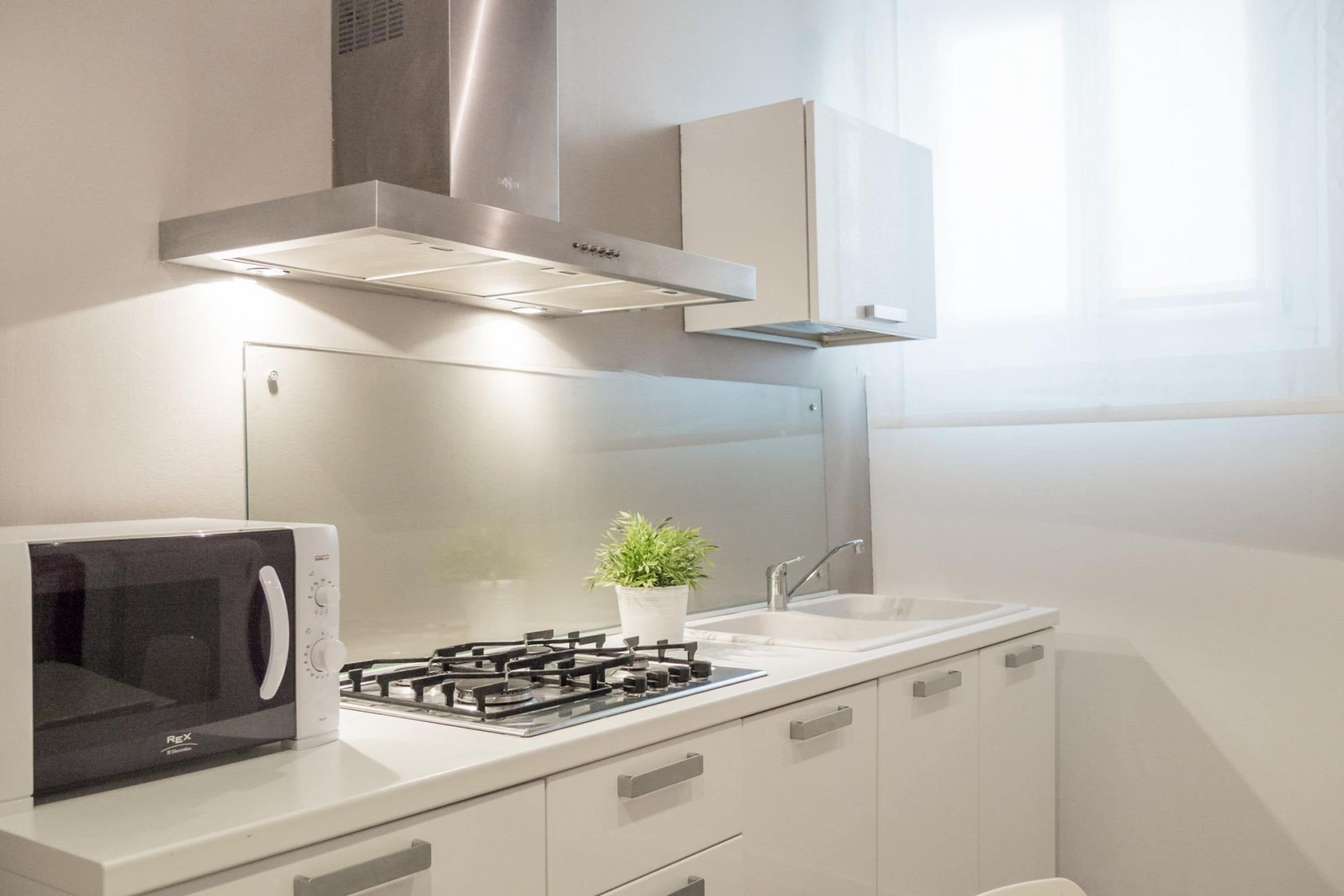 A modern kitchen with a microwave, gas stove, and a potted plant.