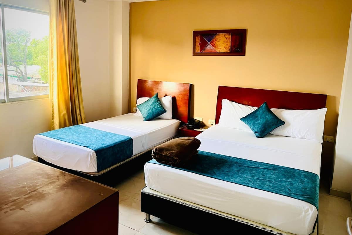 A hotel room with two beds, a wooden headboard, a painting on the wall, and a window with curtains.