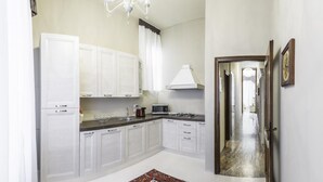 A kitchen with white cabinets, a microwave, a gas stove, and a chandelier. - San Marco Deluxe Canal View Balcony by Wonderful Italy (Venice)