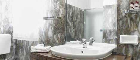 Et badeværelse med vask af marmor, et spejl og et toilet.