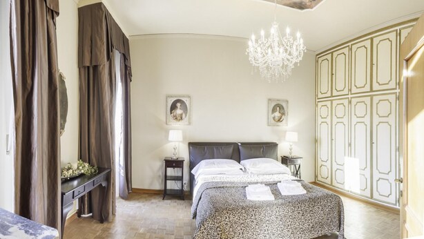 A bedroom with a bed, two bedside tables, a chandelier, and a wardrobe. - San Marco Deluxe Canal View Balcony by Wonderful Italy (Venice)