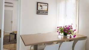 A dining area with a wooden table, white chairs, and a vase of purple flowers. There is a framed picture on the wall with the text "coffee" and "best in." - Accademia Charm 6 by Wonderful Italy (Venice)