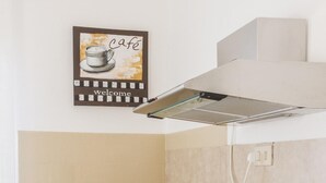 A kitchen with white appliances, a toaster, a plant, and a 'cafe welcome' sign. - Accademia Charm 6 by Wonderful Italy (Venice)