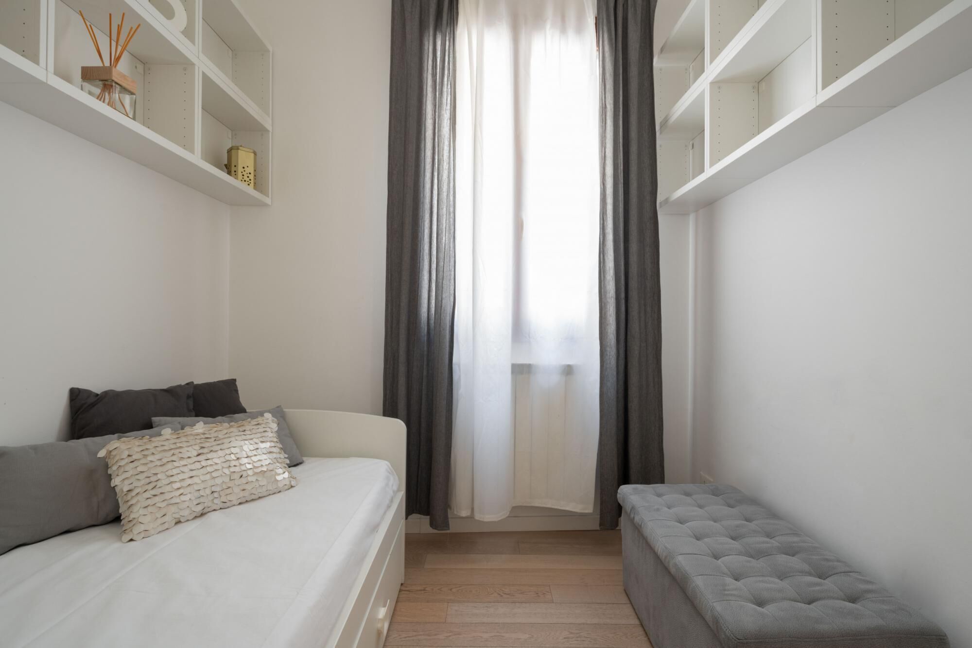 Une chambre à coucher avec un lit, un banc et une fenêtre avec des rideaux.