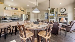 A spacious living area with a dining table surrounded by wooden chairs, a fireplace, and a television.