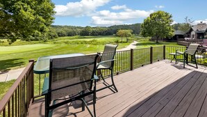 A wooden deck with outdoor furniture overlooking a golf course.