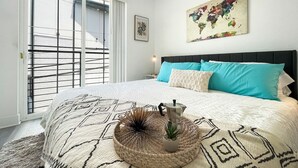 A bedroom with a large bed, a world map artwork, and a coffee pot on the bed. - Capitol Hill Scenic Unit with Bright City Views (Washington)