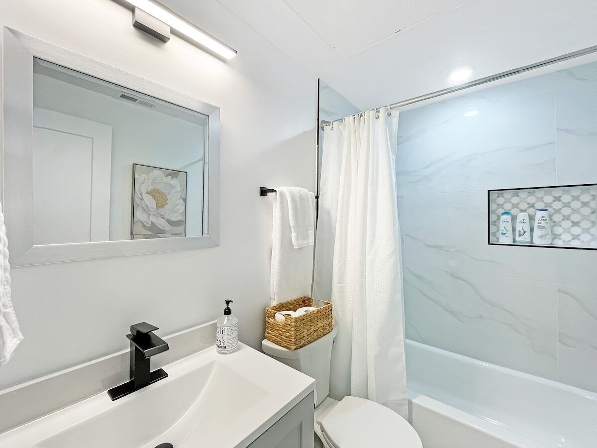 Ein modernes Badezimmer mit einem weißen Waschbecken, Spiegel und Dusche.