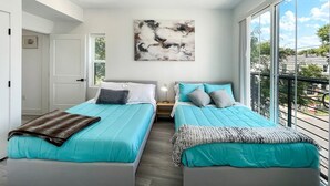 A modern bedroom with two beds, a large window, and a ceiling light. - Capitol Hill Scenic Unit with Bright City Views (Washington)
