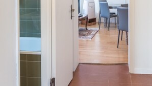 A modern interior with a glass shower, a dining area with chairs and a table, and a hallway with a door leading to the shower. - San Marco Penthouse by Wonderful Italy (Venice)