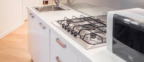 A modern kitchen with a gas stove, a microwave, a sink, and a potted plant on the countertop.