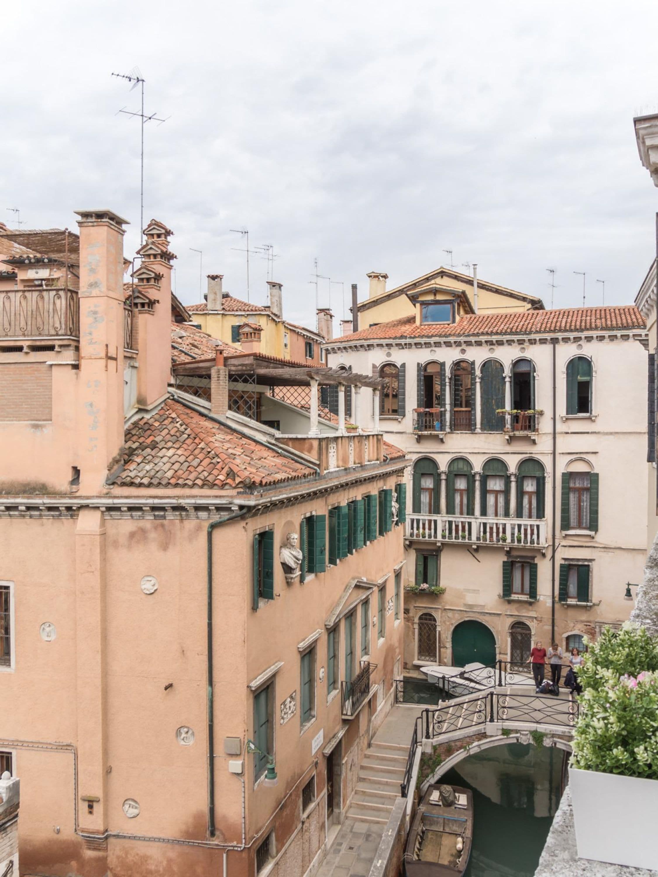 A narrow Venetian canal with buildings on either side, featuring balconies and a bridge.