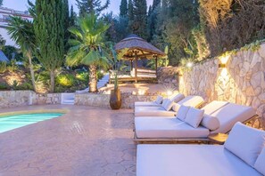A poolside area with lounge chairs, a pergola, and a stone wall. - Brand new Villa With Heated Pool for 8 People (Las Lagunas)