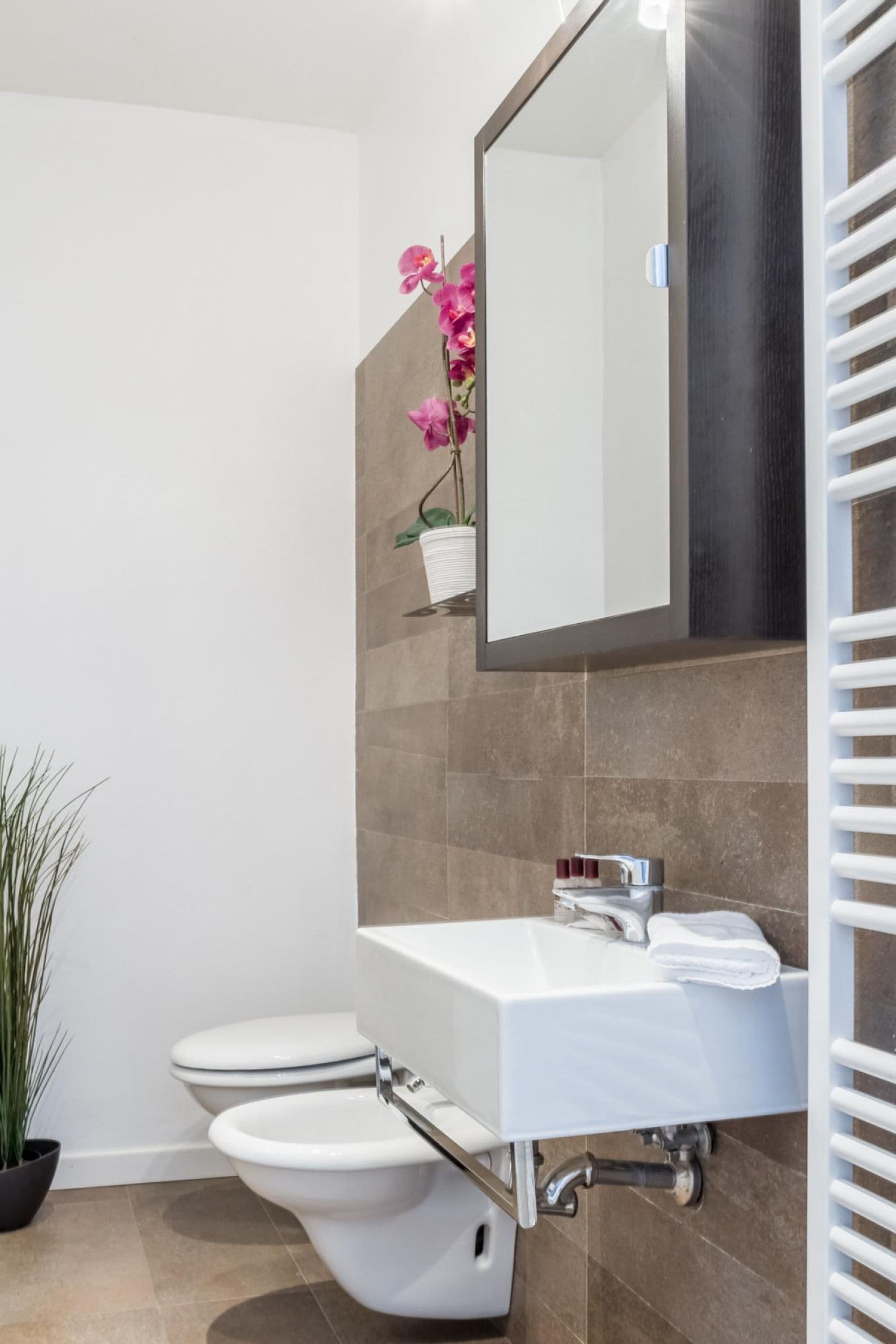 Une salle de bain moderne avec un lavabo blanc, un miroir et des toilettes.