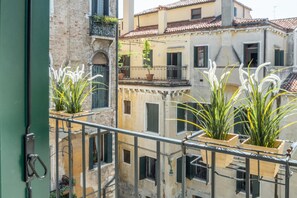 A balcony with potted plants and a view of adjacent buildings.