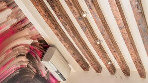 A room with exposed wooden beams, a modern air conditioning unit, and large windows. - Ai Frari Apartment With Balcony by Wonderful Italy (Venice)