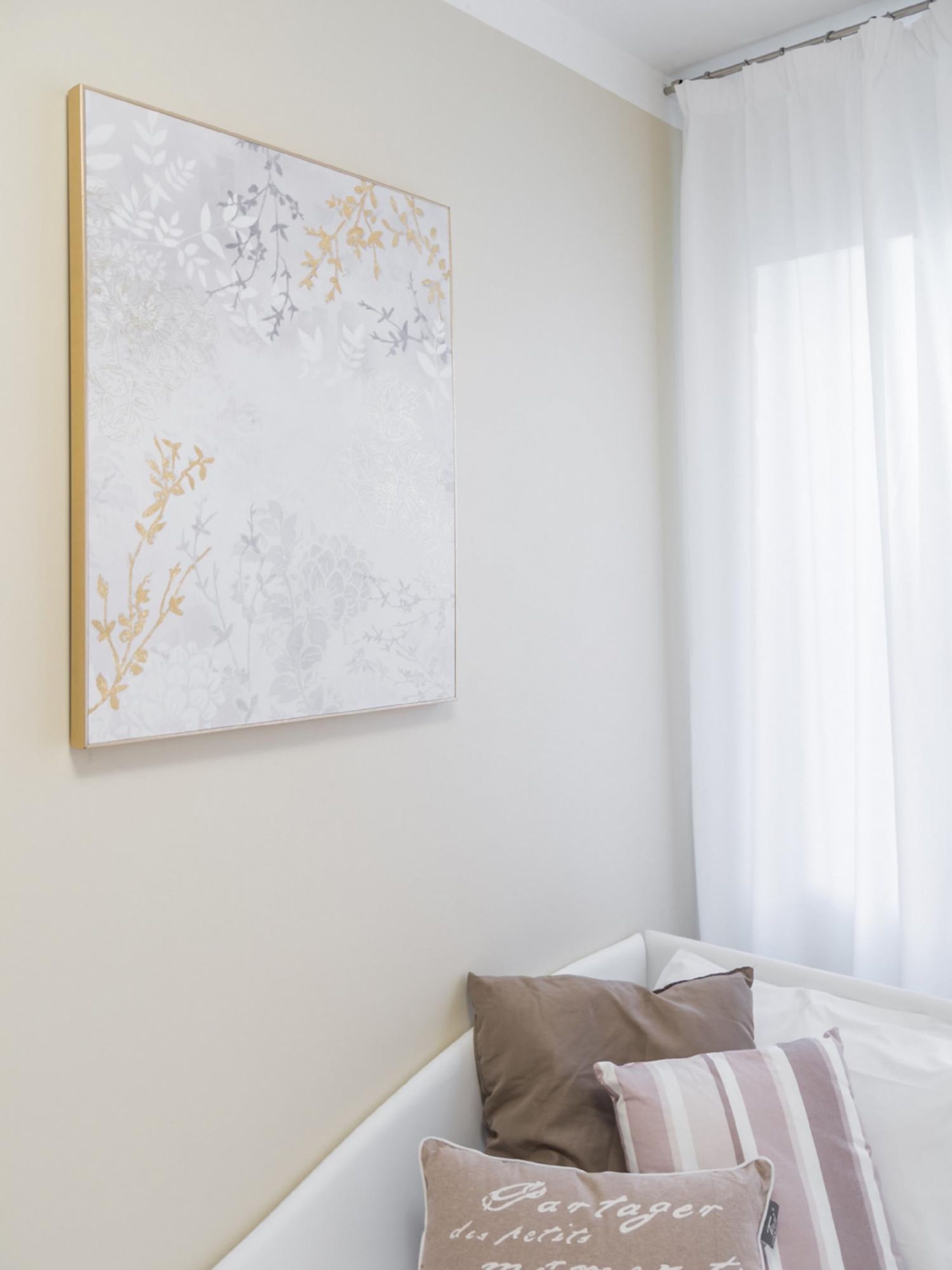 Ein Zimmer mit einem Bett, einem Wandbild und einem fenster mit Vorhängen.