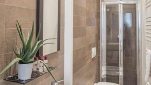 A modern bathroom with a large mirror, a bathtub, a toilet, and a glass-enclosed shower. - Rialto Project Apartment 4 by Wonderful Italy (Venice)
