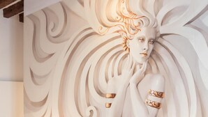 A bedroom with a mural of a woman, a bed with pillows, and bedside lamps. - Rialto Project Apartment 4 by Wonderful Italy (Venice)