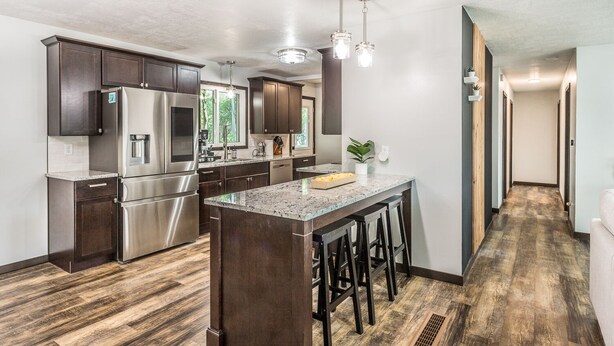 A modern kitchen with dark wood cabinets, stainless steel appliances, and a central island with bar stools. - Cozy Modern Spa ~ Family Fun meets Serene Luxury (Sioux Falls)