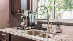 A kitchen with a coffee maker, blender, and a bottle of hand soap. - Cozy Modern Spa ~ Family Fun meets Serene Luxury (Sioux Falls)