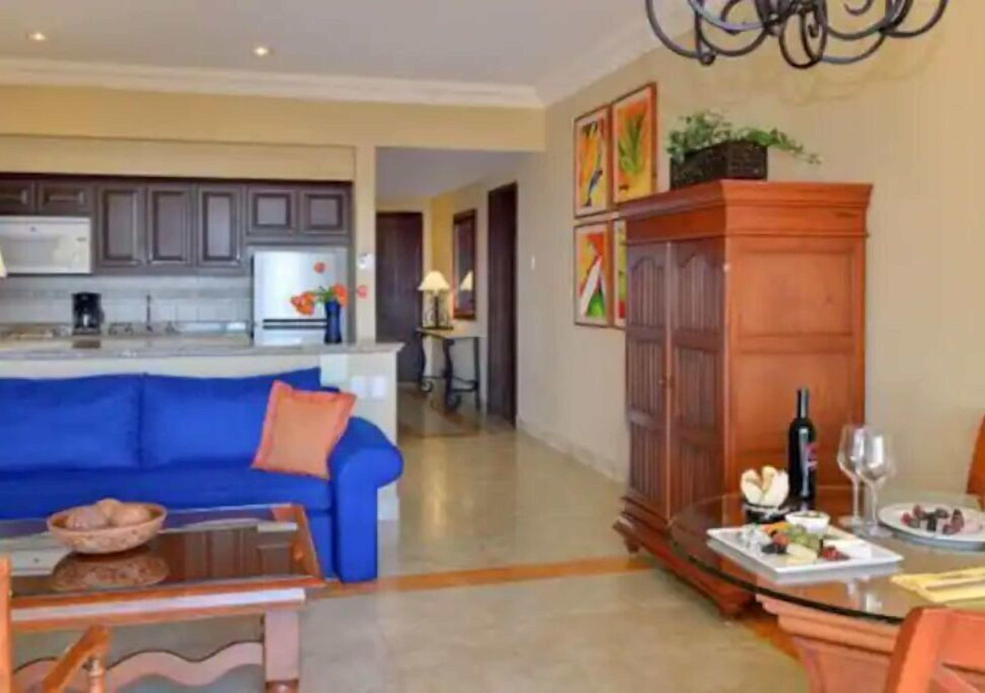 A modern kitchen with grey cabinets, a blue sofa, and a dining area with a table set for a meal.