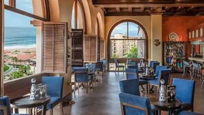 A bar area with a view of the beach, featuring blue chairs and a bar counter. - Studio Priv Balcony PBonito Sunset Beach
 (Paraiso Escondido)