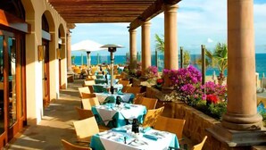 An outdoor dining area with tables and chairs, a wooden pergola, and a view of the ocean. - Studio Priv Balcony PBonito Sunset Beach
 (Paraiso Escondido)