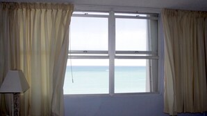 A room with a large window, curtains, and a lamp. - Breathtaking Ocean Front View (Carolina)
