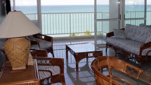 A balcony with a view of the ocean, furnished with wicker chairs, a sofa, and a table. - Breathtaking Ocean Front View (Carolina)