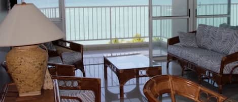 Ein Balkon mit Meerblick, ausgestattet mit Korbmöbeln, einer Couch und einem Tisch.
