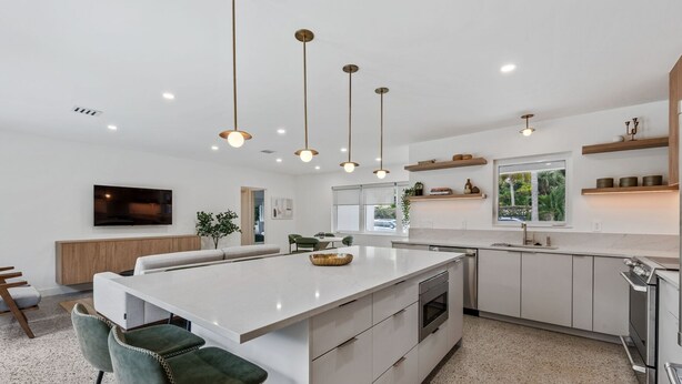 A modern kitchen with a central island, pendant lighting, and a large window providing natural light. - Minimalist Luxury in Historic WPB-Great Location Near Town, Beach, Sites! (West Palm Beach)