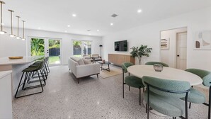 A modern kitchen with a dining area, a sofa, and a TV. - Minimalist Luxury in Historic WPB-Great Location Near Town, Beach, Sites! (West Palm Beach)