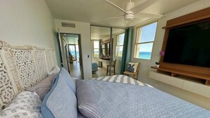 Un dormitorio con una cama grande, televisión y vistas al mar.
