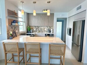 A modern kitchen with a large island, stainless steel appliances, and wicker bar stools. - Beachfront 3 Bdrm Gem in Isla Verde  Walk 2 Eat (Carolina)