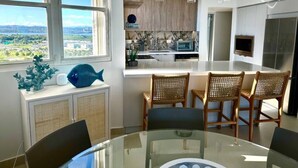 Una cocina moderna con vistas a un paisaje urbano, un comedor con sillas de mimbre y una mesa de vidrio.