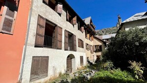 A narrow alleyway with buildings featuring wooden shutters and a rustic stone facade.