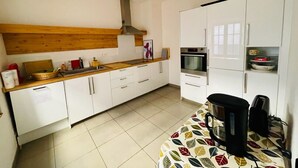 A kitchen with white cabinets, a wooden countertop, a coffee maker, and a toaster.