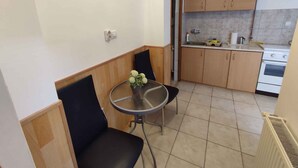 A compact kitchen with wooden cabinets, a small dining table, and a chair. - Studio near the beach with WLAN and air conditioning (Siófok)