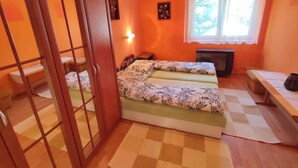 Une chambre avec deux lits, un bureau, une chaise, un radiateur et une fenêtre avec des rideaux.