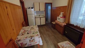 Une cuisine compacte dotée de meubles en bois, d’un réfrigérateur, d’un four à micro-ondes et d’un coin repas avec une table et des chaises.