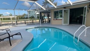 A swimming pool with a covered area, a door leading to a building, and a clear sky.