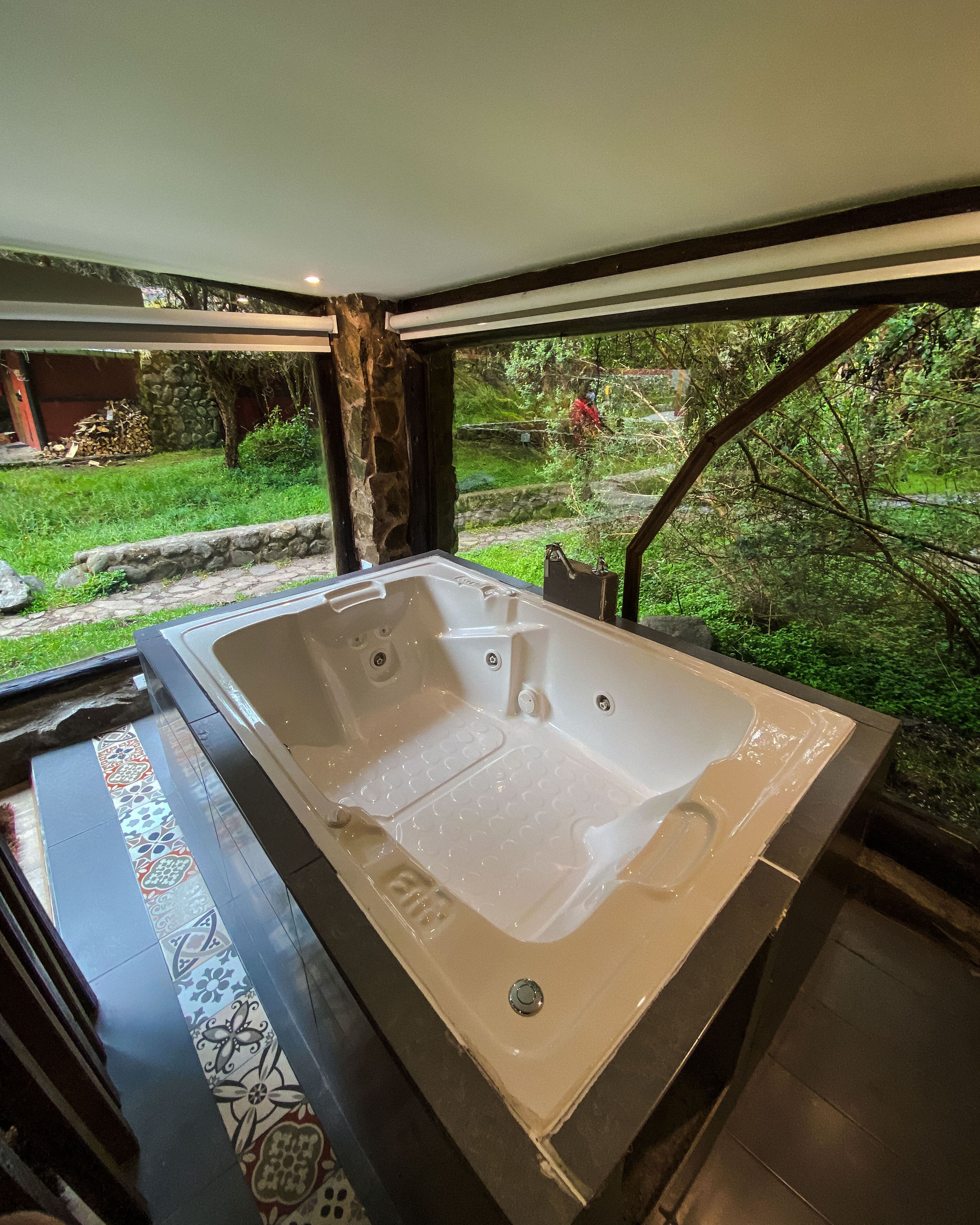 Un grand jacuzzi intérieur avec vue sur un jardin et un mur en pierre.